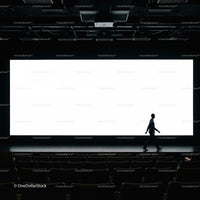 Silhouette of man walking in empty theater with bright screen