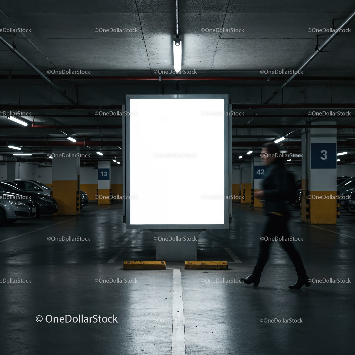 Kobieta przechodzi obok oświetlonego billboardu na krytym parkingu