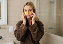 Woman in Spa Room Applying Gold Eye Patches for Skin Care