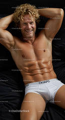 Smiling muscular man relaxing on black bedding in white briefs