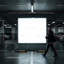 Man walking past illuminated billboard in parking garage