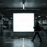 Man walking past illuminated billboard in parking garage