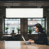 Focused woman working on laptop in modern cafe setting