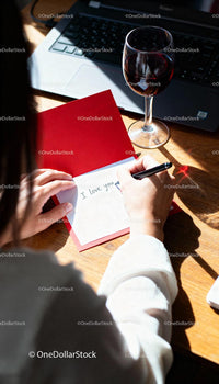 Writing a heartfelt love note with glass of red wine