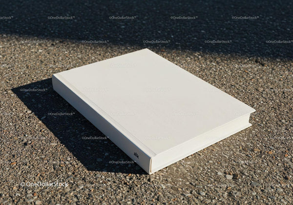 Minimalist white book laying on textured pavement JPG Mockup Image