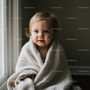 Toddler wrapped in soft blanket by window light