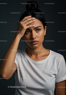 Woman with Hand on Forehead Expressing Stress or Anxiety in Studio