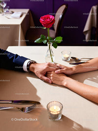 Romantic couple holding hands at candlelit dinner table