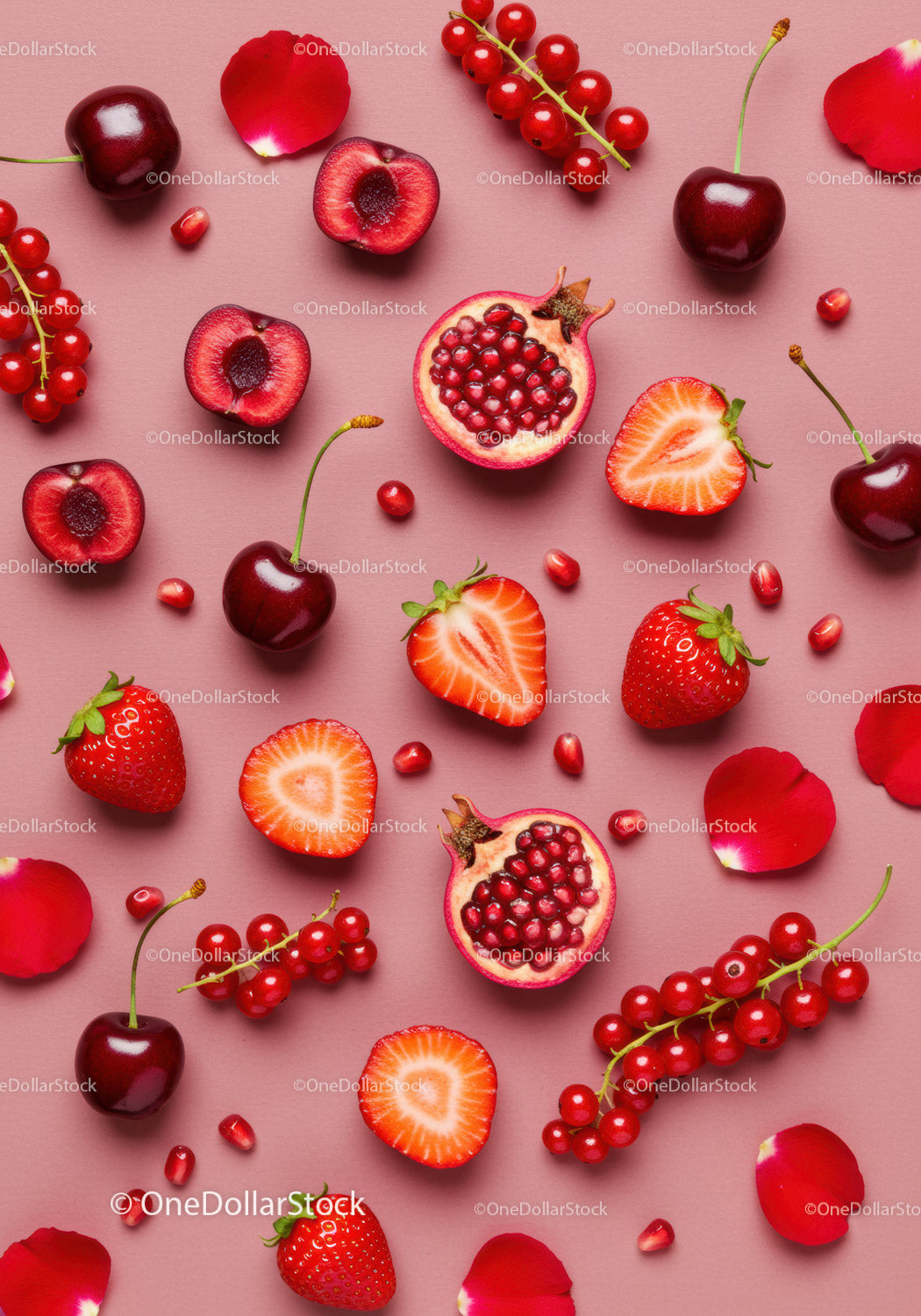 Assorted red fruits and rose petals on pink surface