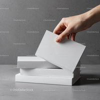 Hand Reaching for a Blank White Book on Stack