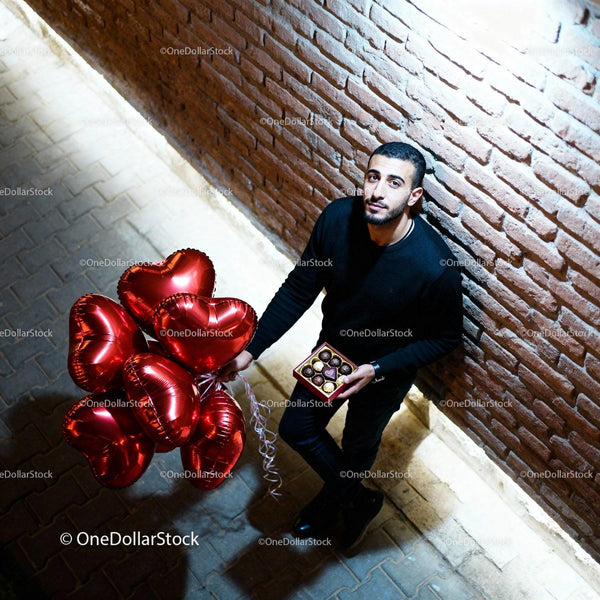 Man Holding Red Heart Balloons and Chocolates Outdoors