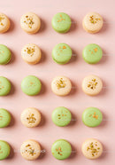 Assorted pistachio and vanilla macarons on pastel background