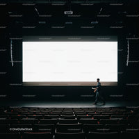 Man Walking Across Dark Theater Stage With Large Screen