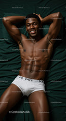 Smiling muscular man relaxing on dark green bed linen
