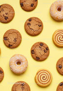 Assorted cookies and donuts on yellow background