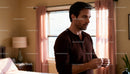 Thoughtful man standing in softly lit cozy bedroom