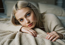 Portrait of a Young Woman Relaxing on Cozy Beige Blanket with Blue Eyes