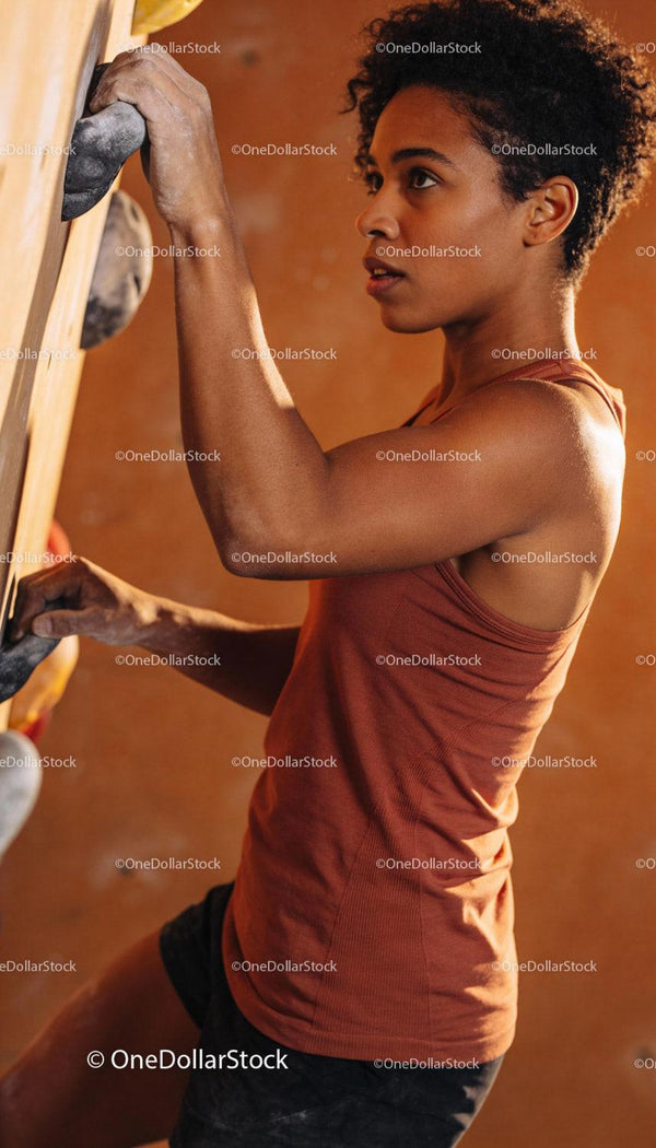 Focused young woman climbing indoor bouldering wall