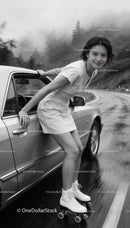 Young woman roller skating beside car on rainy road