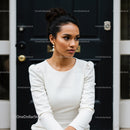 Elegant young woman in white dress sitting outdoors