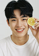 Young Man with Bright Smile Holding Lemon Slice in White Background