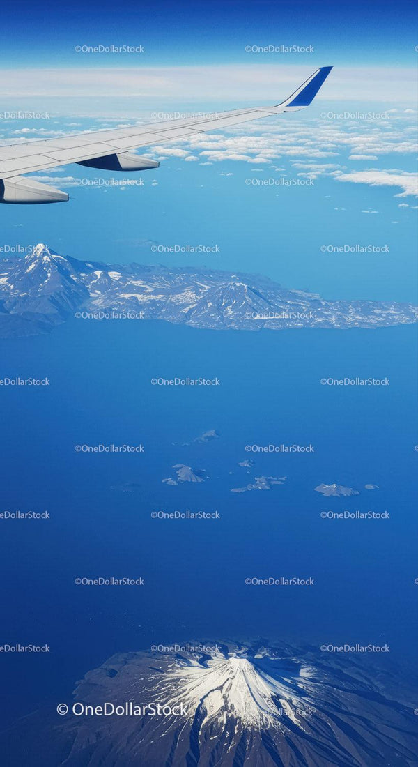 Aerial View of Snow-Capped Volcano and Mountain Range from Airplane Window