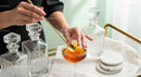 Elegant Amber Cocktail with Crystal Decanters and Gold Spoon
