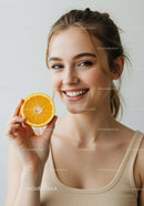 Young Woman with Bright Smile Holding Orange Slice in Natural Light