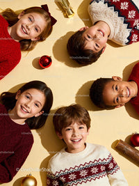 Smiling children in festive sweaters lying on floor