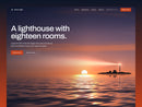 Outer Light hotel template hero: a sunrise over a calm sea with a lighthouse on a small islet sweeping its beam, the headline A lighthouse with eighteen rooms and a vermilion Book a room button